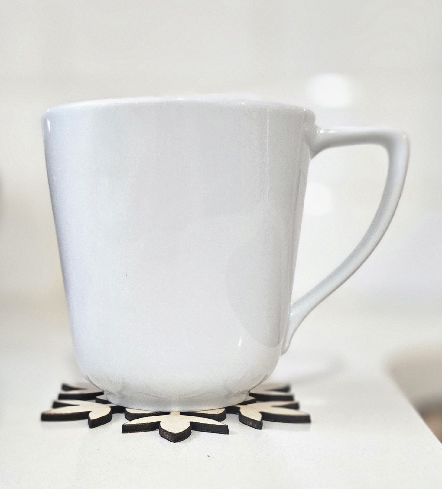 White mug resting on a laser-cut wooden snowflake coaster by PetiteTrace